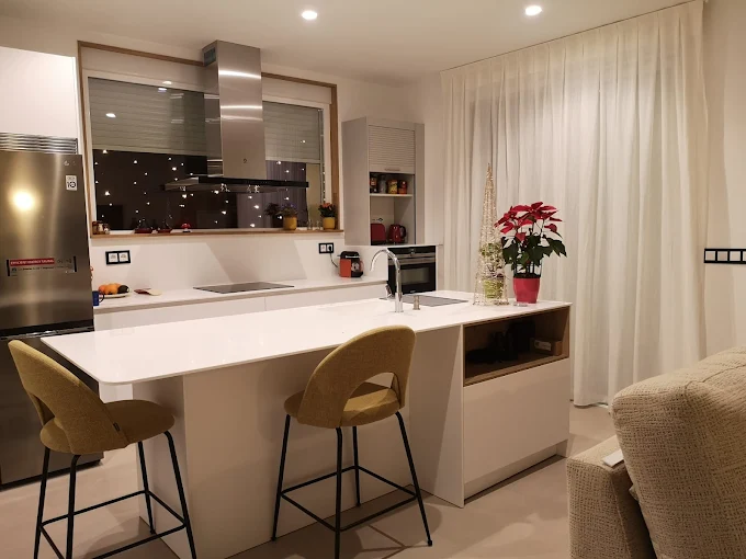 Cocina moderna con isla central de madera, electrodomésticos de acero inoxidable y iluminación colgante elegante.