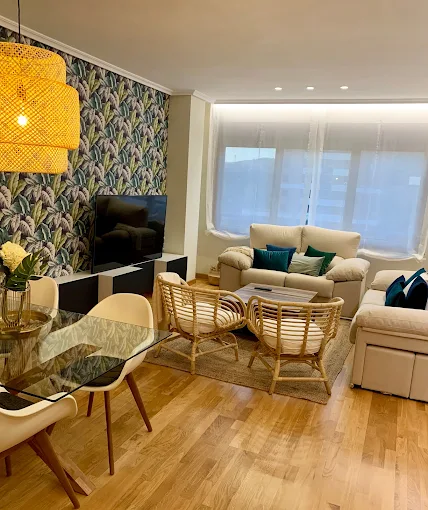 Salón moderno con sofá amplio y decoración minimalista, iluminación natural y suelo de madera.