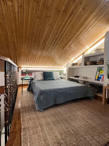 Dormitorio principal con cama de matrimonio, iluminación LED y detalles en madera natural.