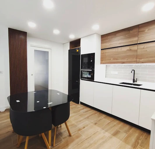 Cocina de diseño abierto con encimeras de mármol, muebles blancos y electrodomésticos eficientes.