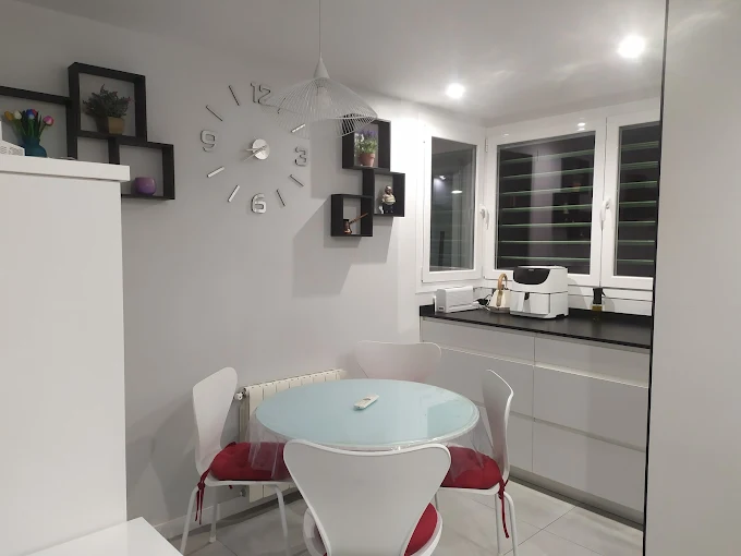 Comedor con mesa de madera maciza y sillas tapizadas, lámpara colgante y decoración elegante.